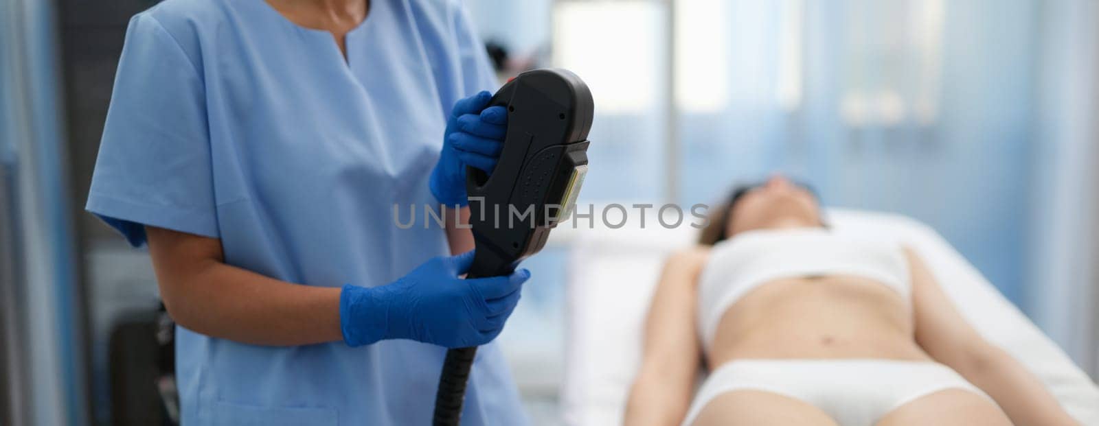Beautician holding hybrid laser hair removal machine in beauty salon closeup. Aesthetic medicine laser hair removal concept
