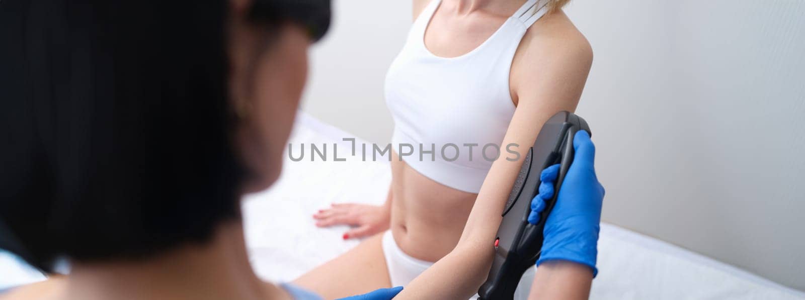 Beautician removing unwanted hair from client arm with laser closeup. Skin care laser hair removal concept