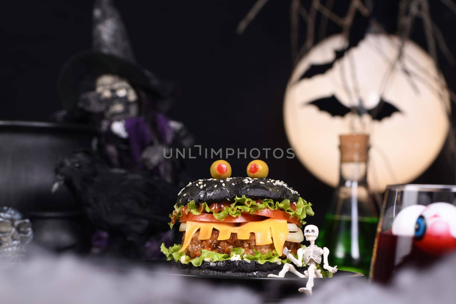 Monster Burger. Black bun, juicy beef cutlet, lettuce, onion, tomato and cheese in the shape of teeth, eyes with olives. Definitely a pick-me-up and a perfect Halloween party appetizer.