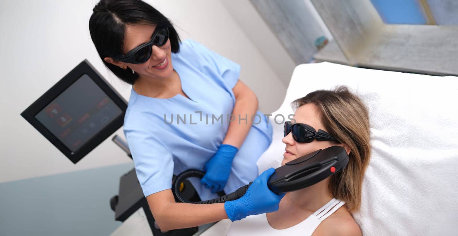Beautician removing unwanted facial hair of client using laser in beauty salon. Aesthetic medicine laser hair removal concept