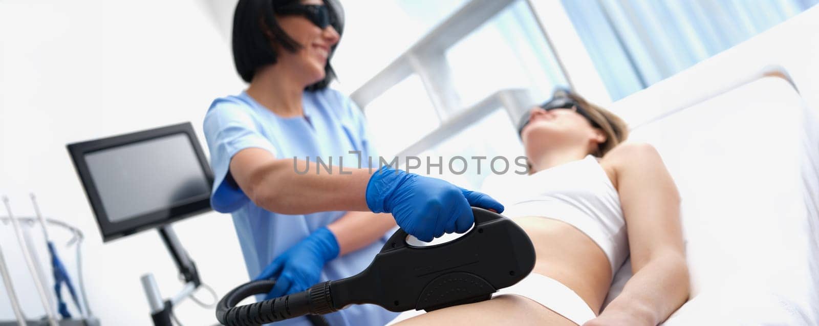 Beautician doing laser hair removal bikini area clients in beauty salon closeup. Beauty services for unwanted hair removal concept