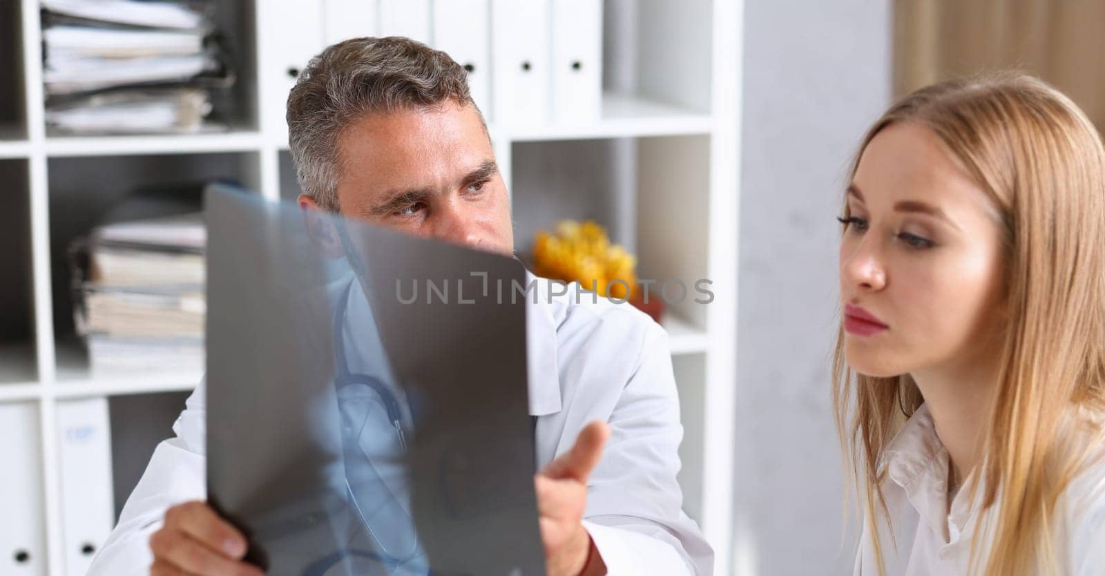 Portrait of doctor talking with colleague about leg x ray result, doc need advice from coworker. Recovery, medicine, healthcare, injury, treatment concept