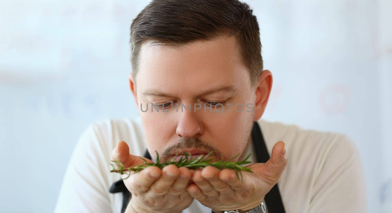 Portrait of professional chef smell twig of rosemary, herb add to dish, better taste with greenery. Cooking as hobby, enjoy delicious food. Eating concept