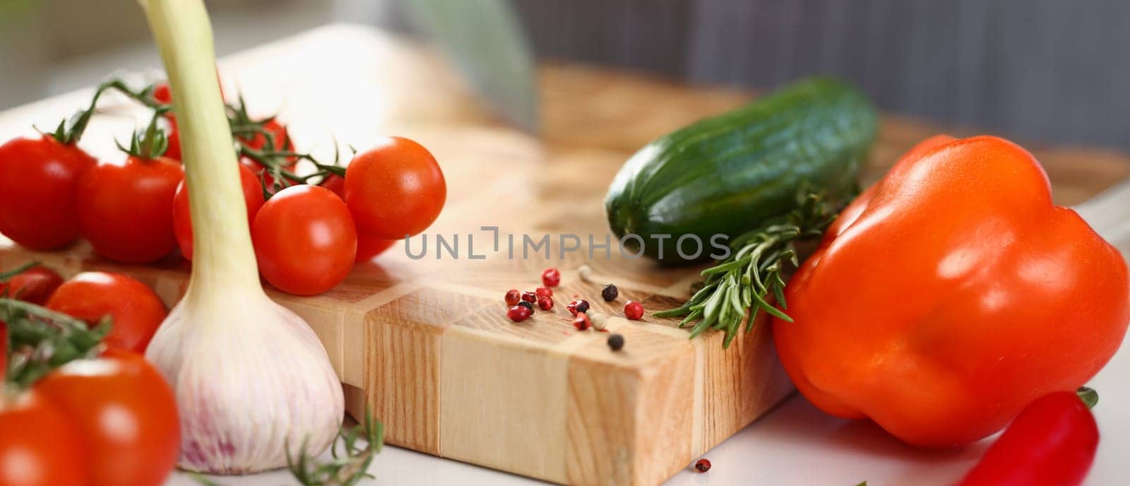 Close-up of wooden cutting board with cutted pieces of vegetables, fresh ingredients for salad. Cooking healthy meal for body. Cooking, eating concept