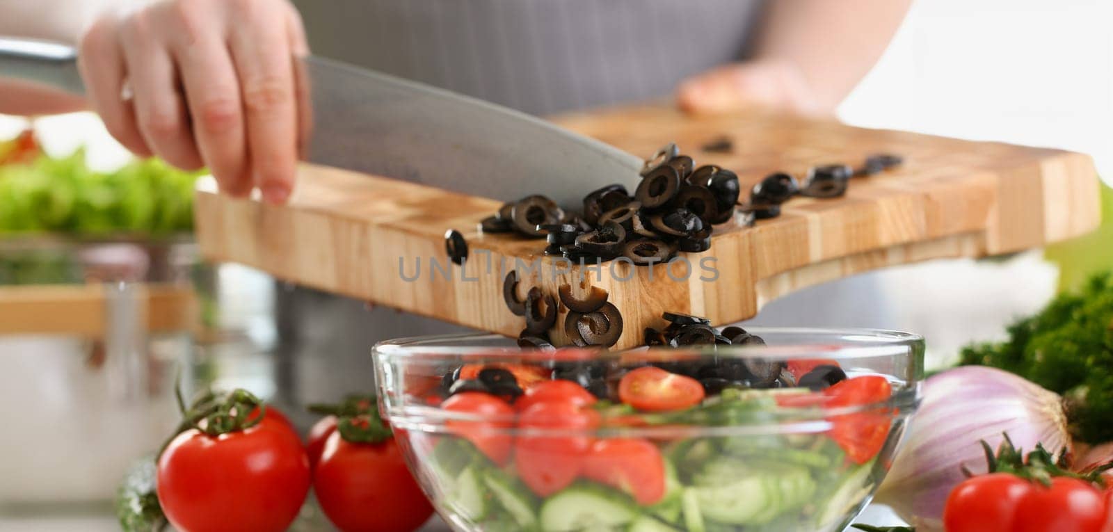 Close-up of man chef cutting olives, ripe vegetable ingredient for fresh spring salad. Cooking meal for family, experiment on kitchen. Food, taste concept