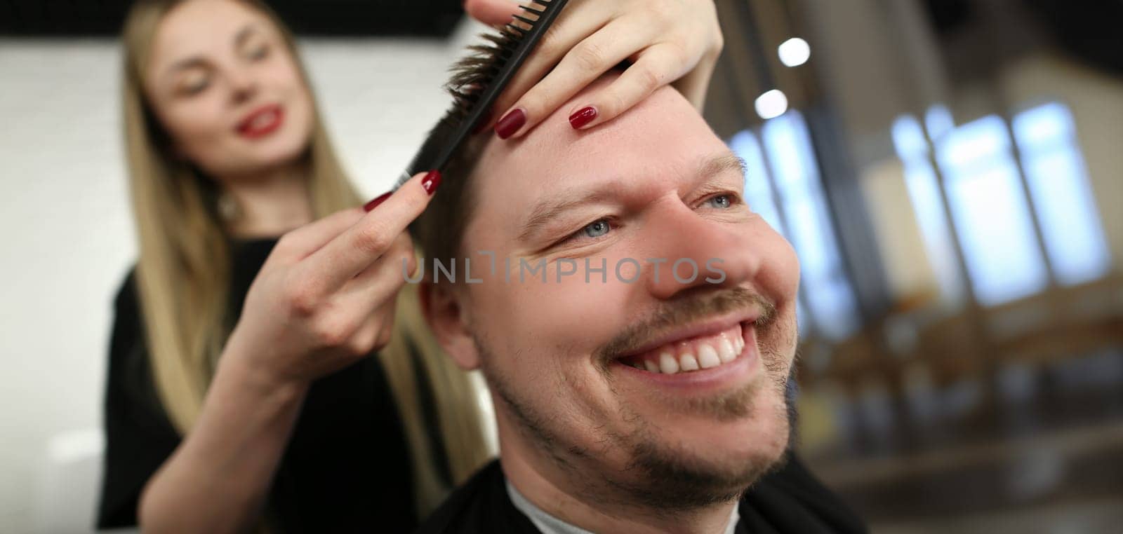 Portrait of female professional hairdresser cutting hair with scissors, smiling male client sit in masters chair. Wellness, barbershop, creativity concept