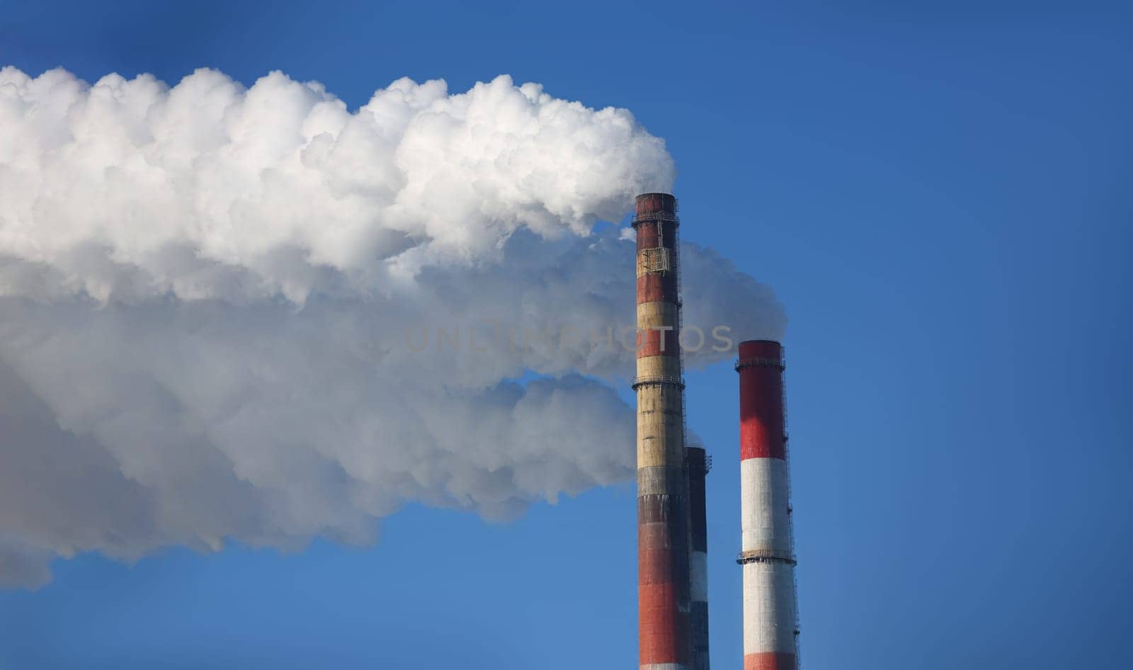 Close-up of power station with three smoke stacks, smoking pipes of heating supplying heat to city. Air pollution, ecology, smog problem, impact concept