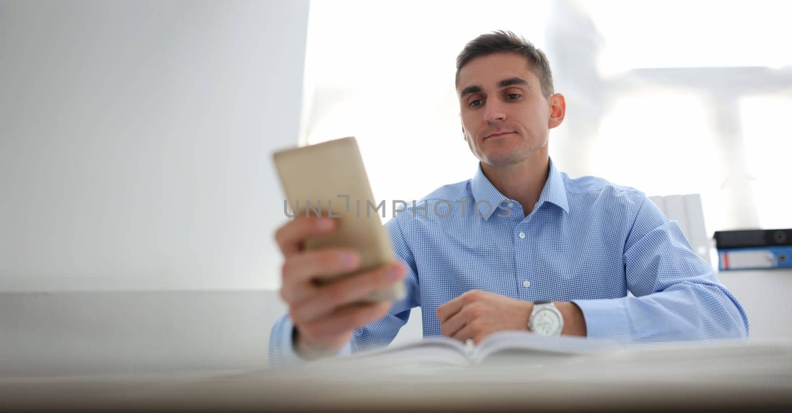 Portrait of concentrated worker using smartphone, chatting or surfing on internet. Kill time at work, bored, addiction, technology, digital world concept