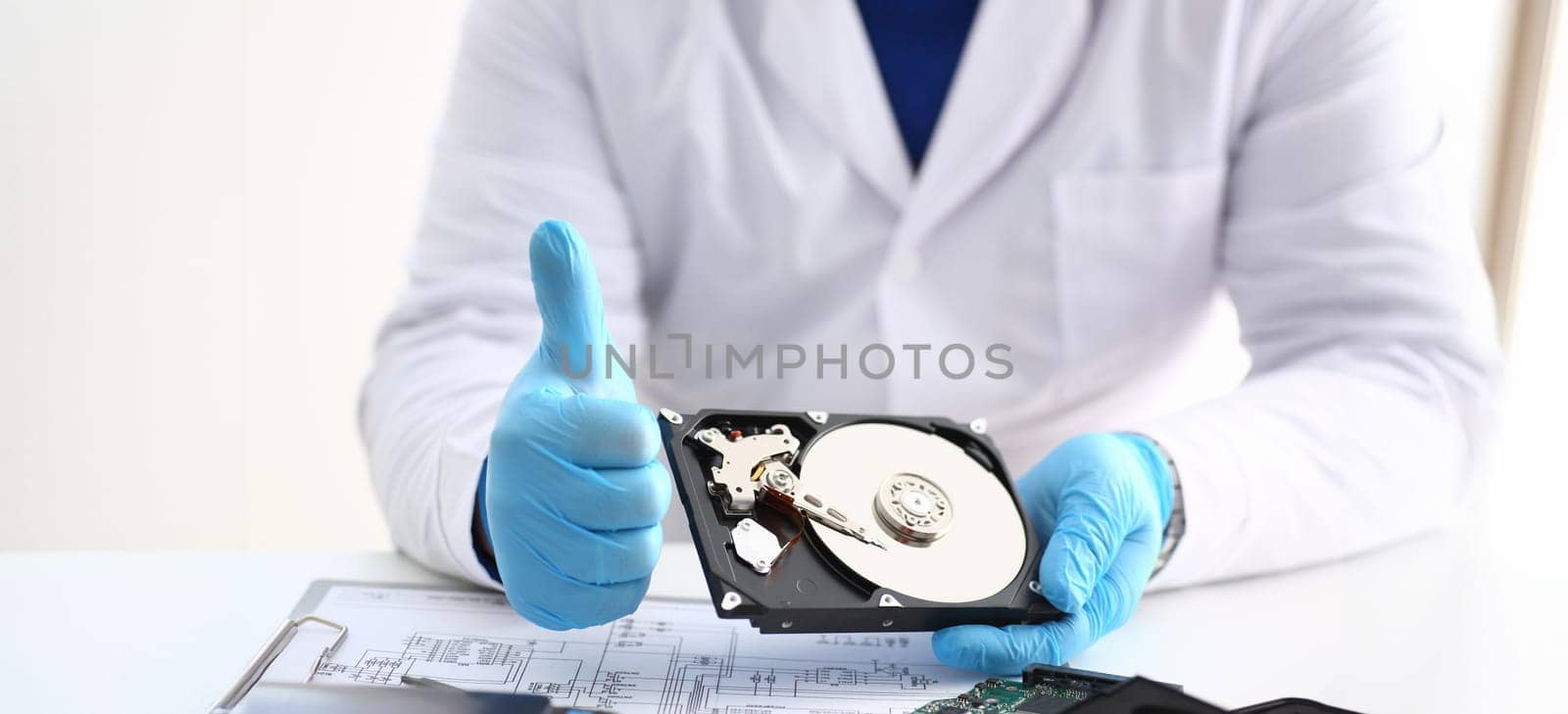 Close-up of man in uniform hold disassembled hard drive from computer, hdd and reader, show thumbs up. Fixed part of computer device. Technology concept