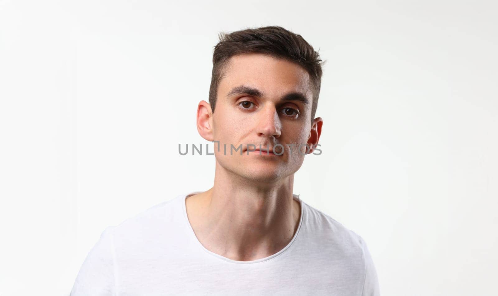 Portrait of young man with serious look, brunette man pose on white background. Handsome male model, attractive guy on photoshot. Modeling business concept
