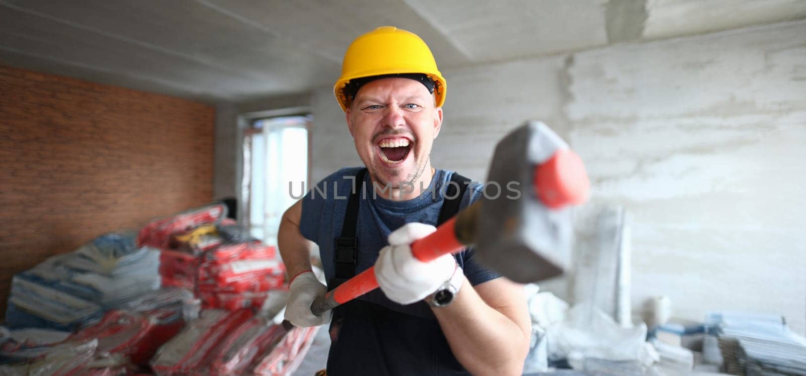 Portrait of happy male excited to start building, worker hold hammer, energetic mood. Crash walls, scream. Renovation, construction site, builder concept