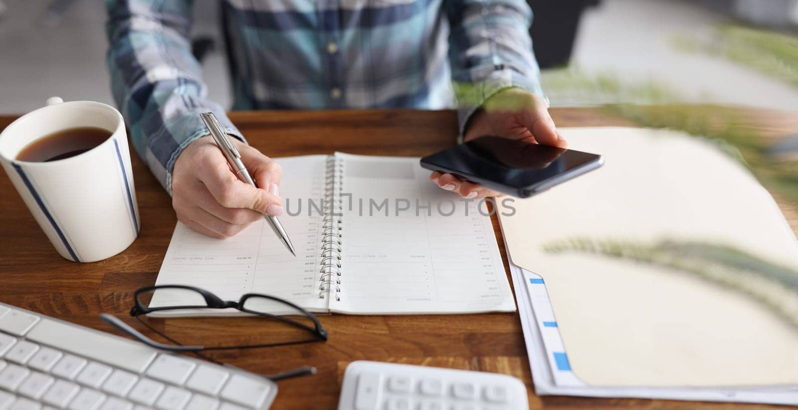 Close-up of person start day right with planner and cup of coffee, make appointment, plan. Journal, diary, creativity, writer, workplace, set goal concept