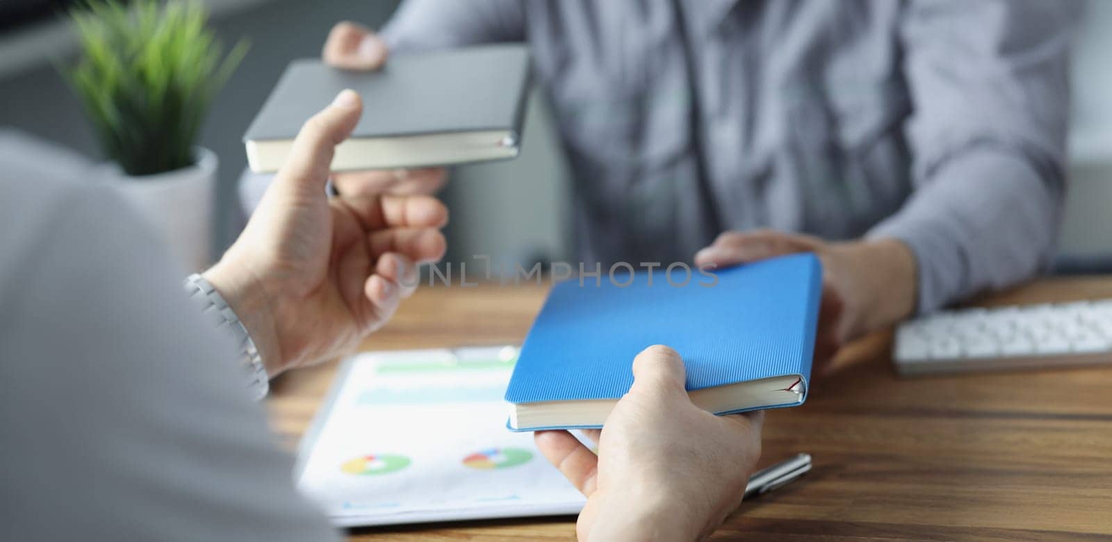Close-up of businesspeople exchange notebooks in office, men give to each other books. Share knowledge, useful information. Business, reading, note concept