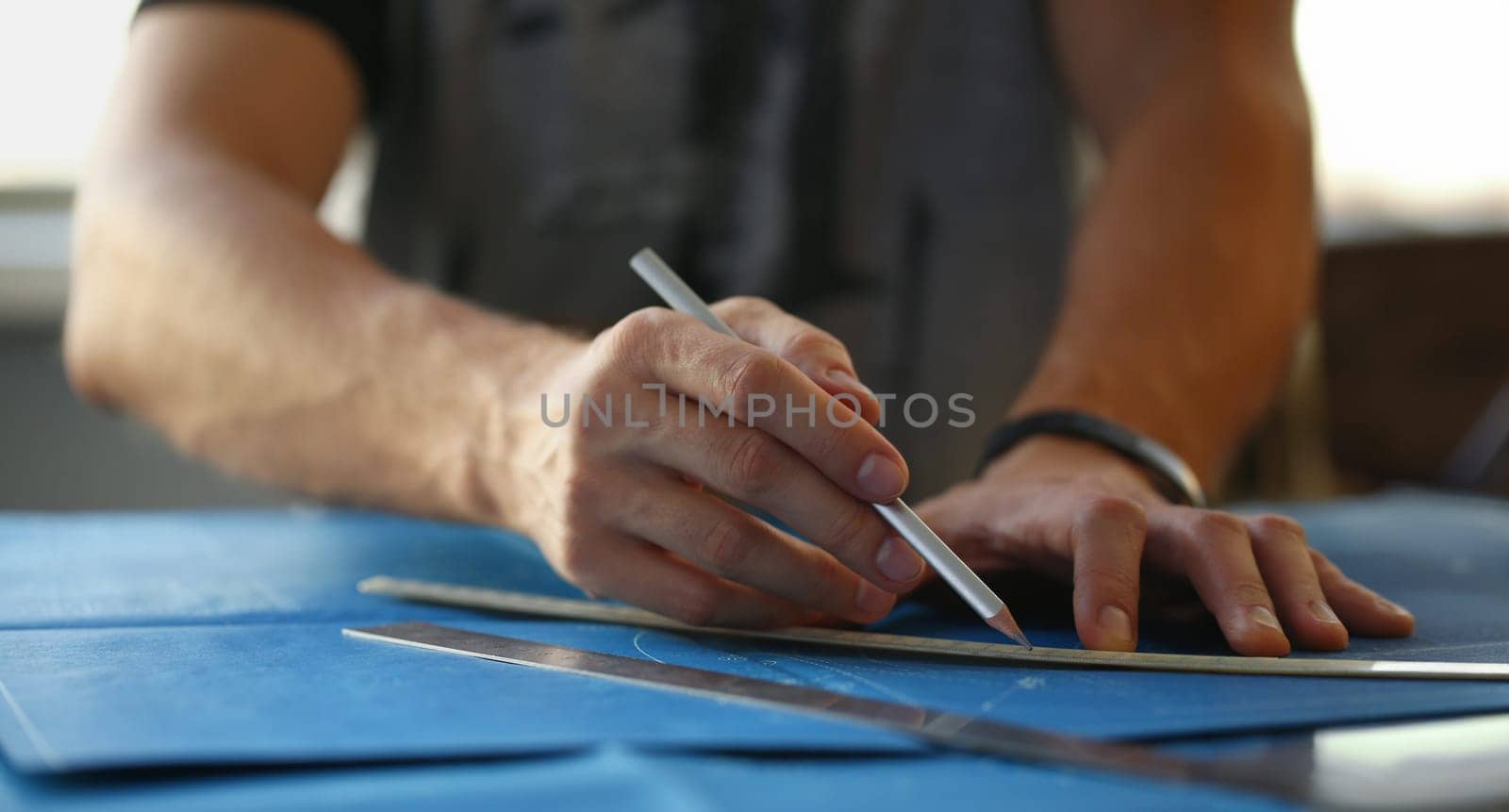 Close-up of builder man hand holding pencil and make corrections on building plan. Engineering blueprint design for buildings on desk. Architecture concept