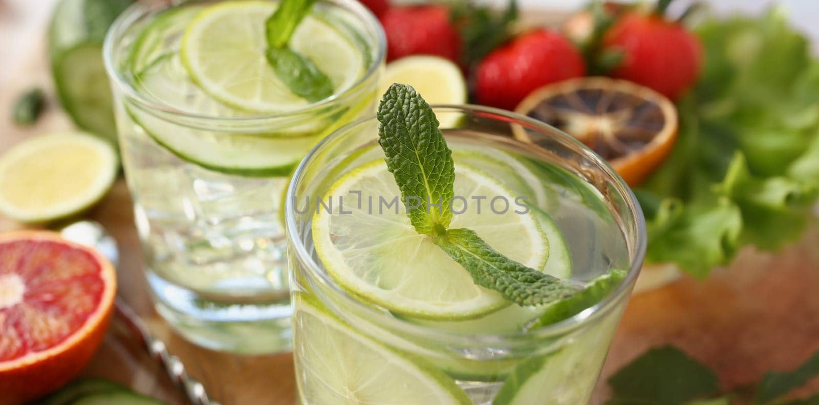 Close-up of cooling drinks cocktails in glasses on table, lime with lemon and mint, cheers or toast. Summer fruit beverages for company. Party, fun concept