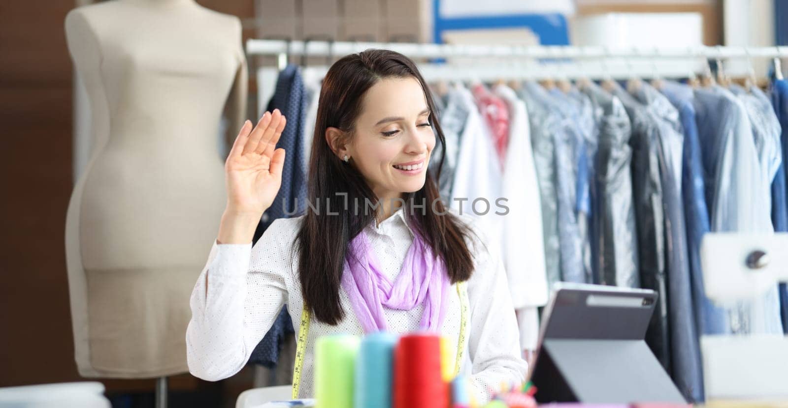 Woman fashion stylist greets customer remotely on tablet. Order tailoring online concept