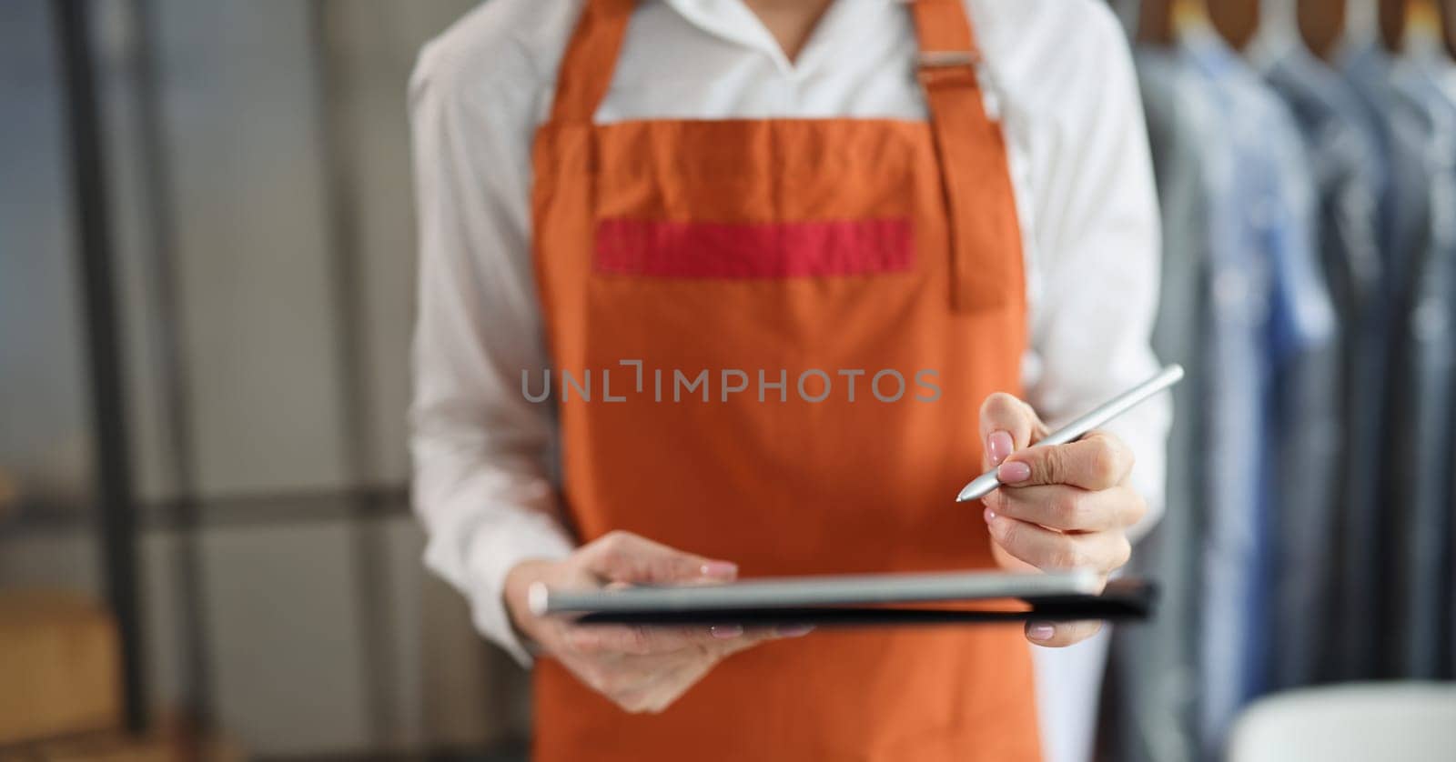 Tablet with stylus in female hands in uniform. Receiving and issuing order concept