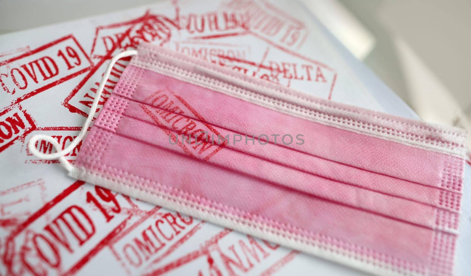 Pink medical mask with omicron print. Different new stamps coronavirus infection concept