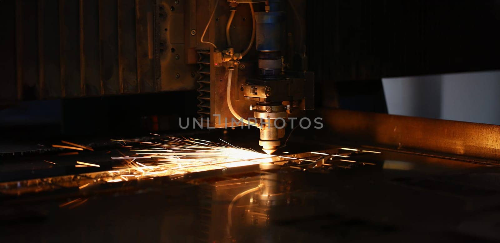 Close-up of sparks fly out of automated machine, metal processing laser on metallurgical background. Manufacturing, parts for automotive production concept