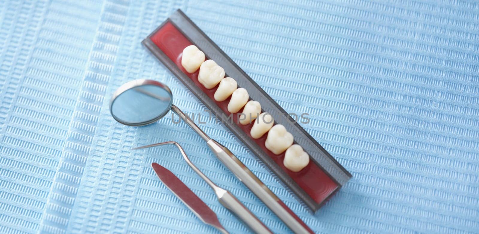 Close-up of set of dentist medical tools to treat people teeth problems. Tiny mirror, teeth sample on surface. Stomatology cabinet, dentistry, oral concept