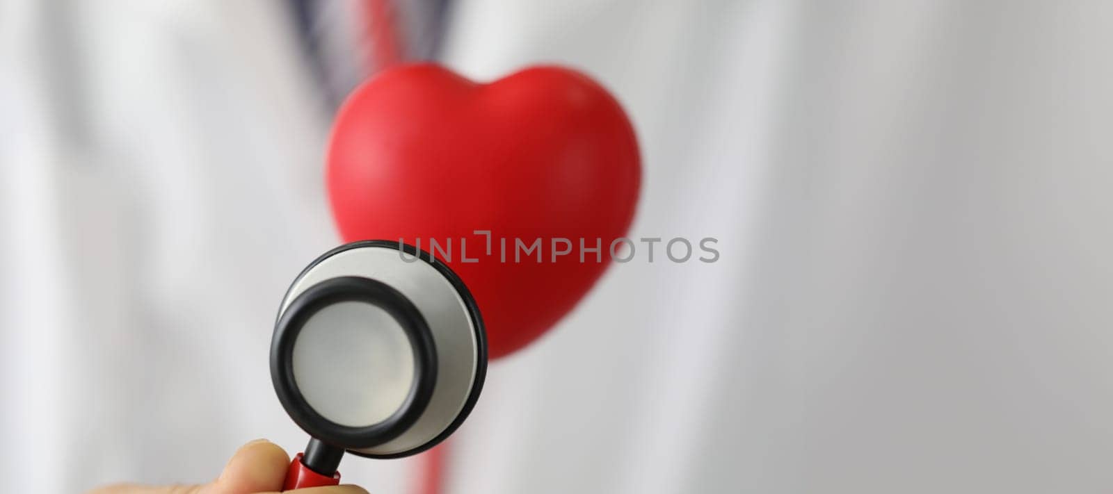 Close-up of medical stethoscope instrument listen to red plastic heart. Save life, full body checkup. Medicine, cardiology, healthcare, analysis concept