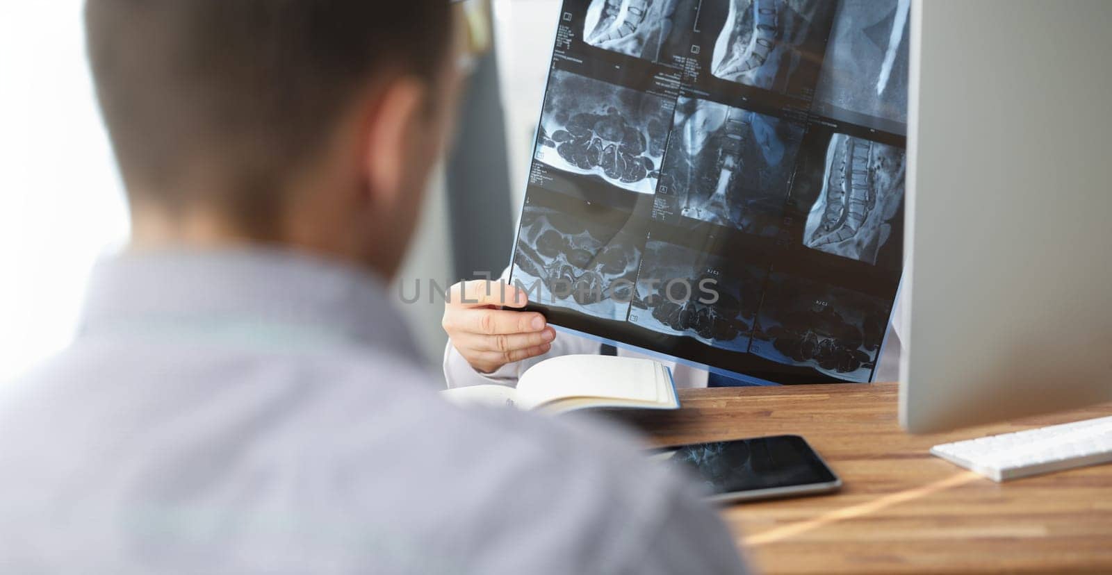 Close-up of doctor examining patients xray result in hospital on appointment with client. Scan of persons back. Healthcare, medicine, diagnostic concept