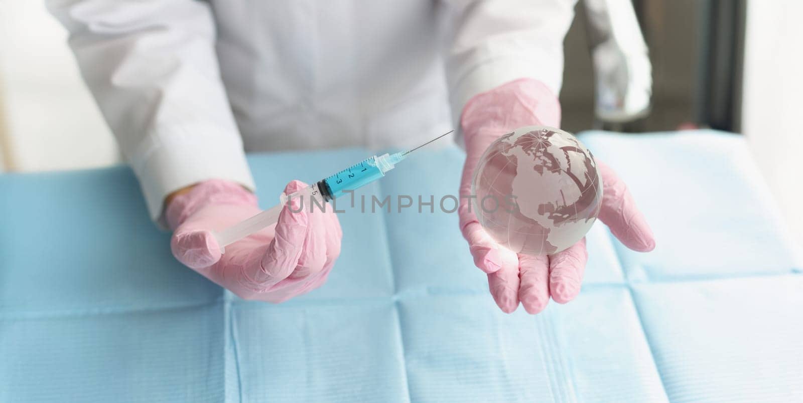 Close-up of medical worker hold syringe and miniature world globe in hands. Coronavirus injection, vaccination. Stop pandemic, shot, immunization concept