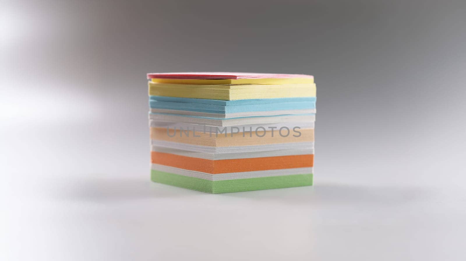 Close-up of uneven stack of sticky post it note on grey surface, bunch of clean papers. Bright pages for writing ideas, plans. Stationery, creative concept