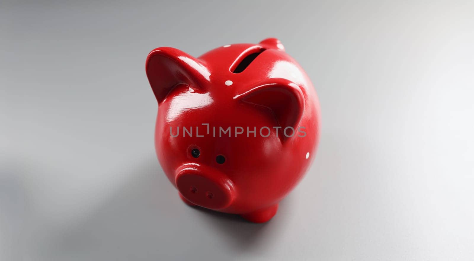 Close-up of bright red piggybank container on grey surface, empty thing to put money. Hole in ceramic animal. Finance, saveup for future, success concept