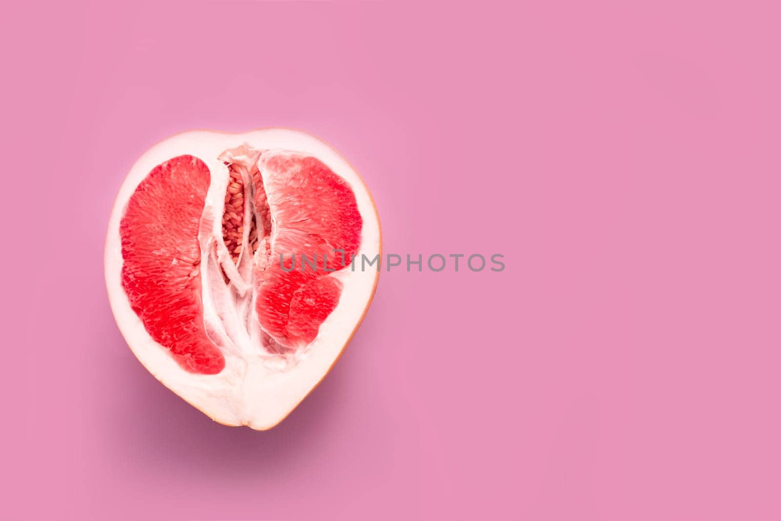 A half peeled grapefruit on a pink colored background. Minimal still life.