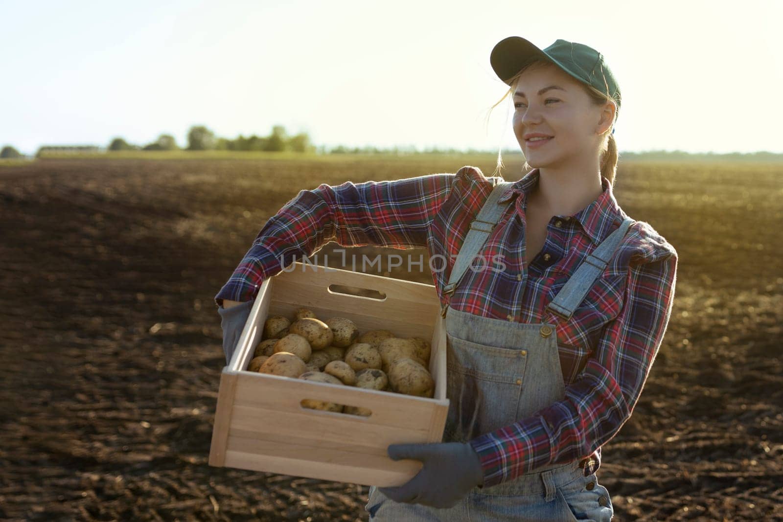 Happy smiling caucasian female potato farmer or gardener. Agriculture - food production, harvest concept.
