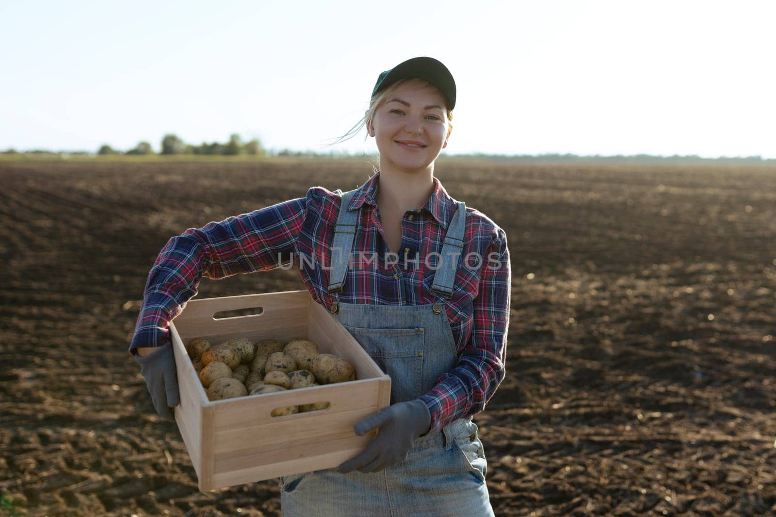 Happy smiling caucasian female potato farmer or gardener. Agriculture - food production, harvest concept.
