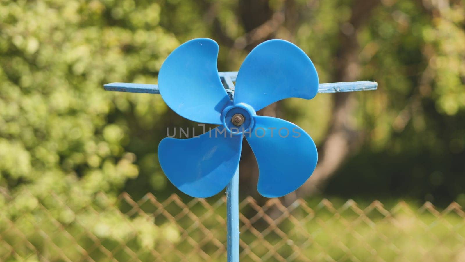 A blue vane weathervane spins in the wind in the summer