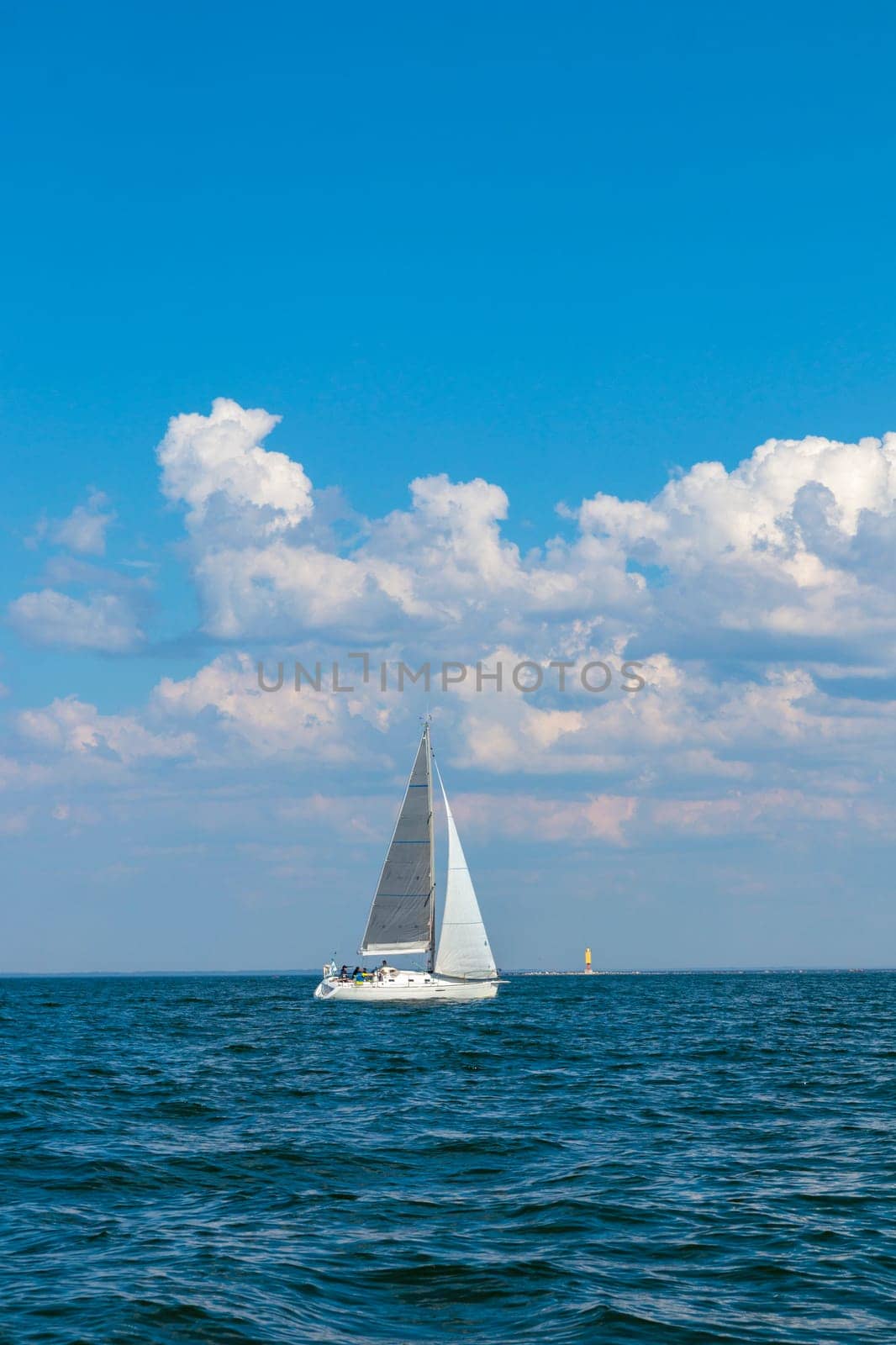 White sloop rigged yacht sailing in the Baltic sea at sunset. Clear sky after the storm, soft sunlight. Transportation, travel, cruise, sport, recreation, leisure activity, racing, regatta