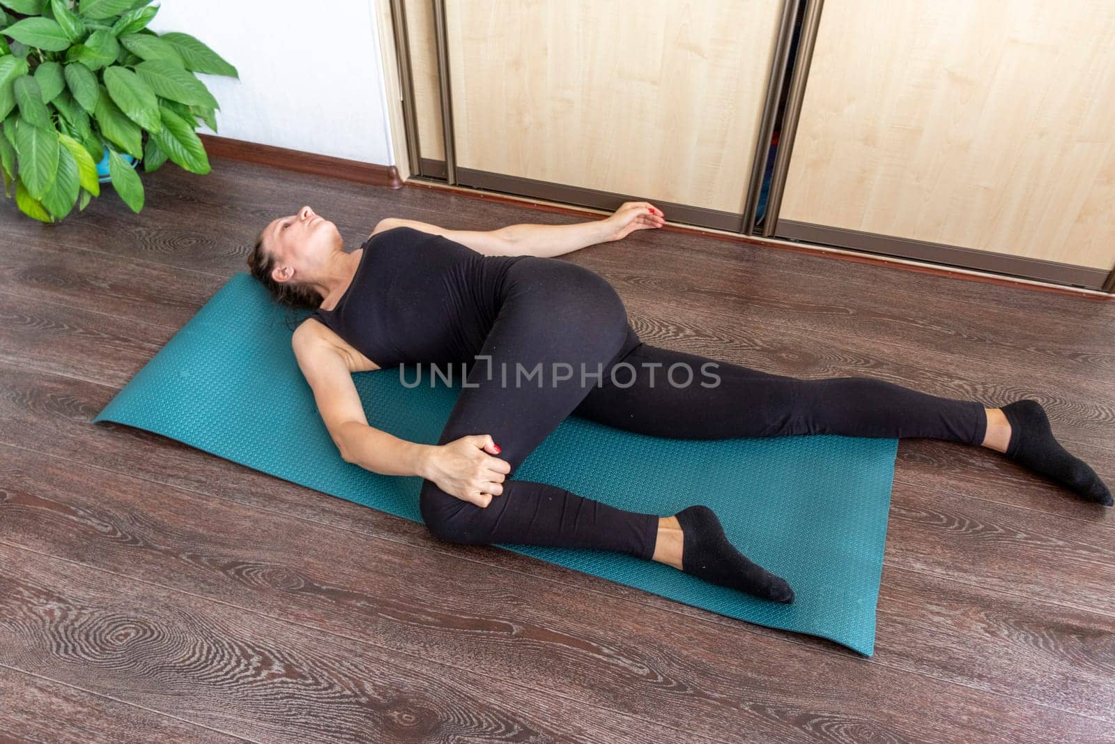 Shot of the woman performing various stretching and physical exercises laying on the yoga mat on the floor
