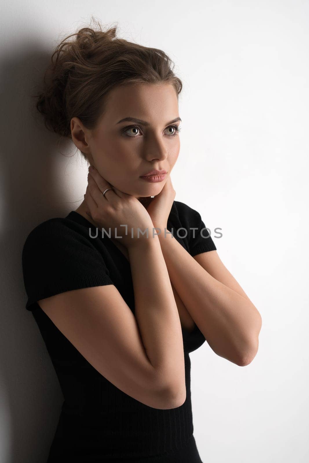 Young pretty blonde in black sexy tshirt with deep decollete posing in studio by the white wall