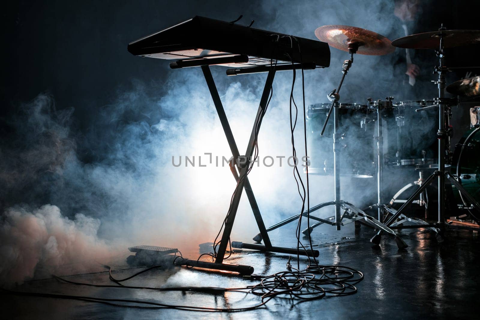 View of modern drum kit and electric piano in dark smoky studio