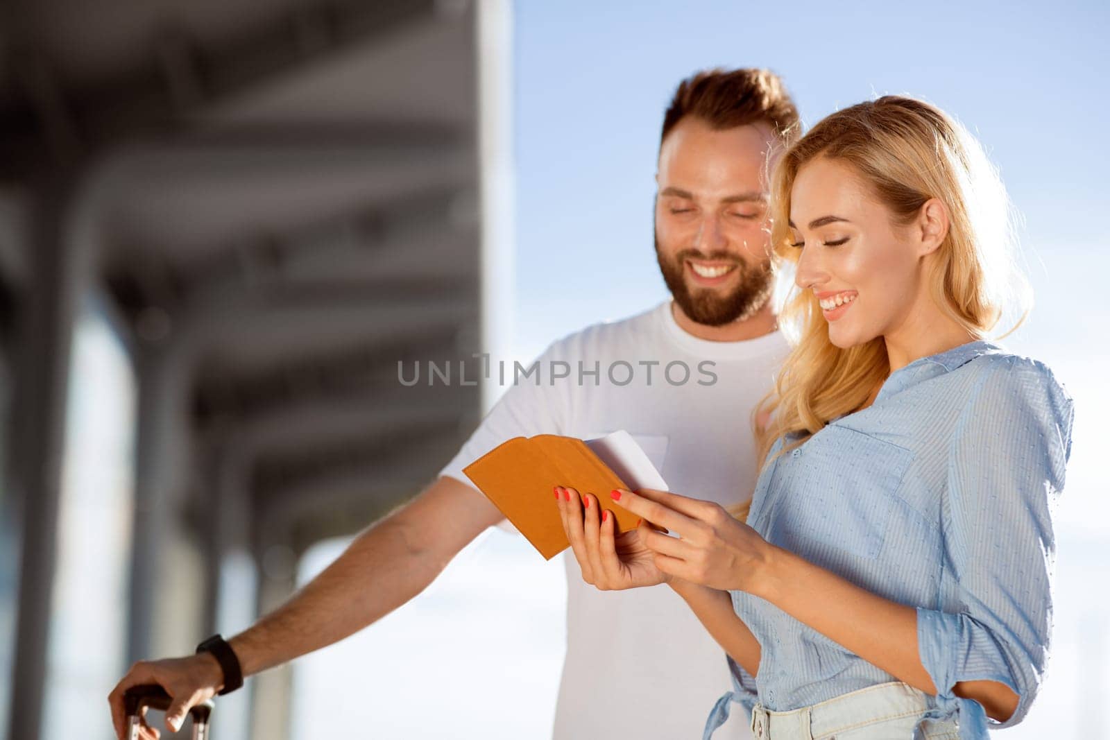 Traveling Concept. Portrait of beautiful couple checking tickets standing outdoors, copy space