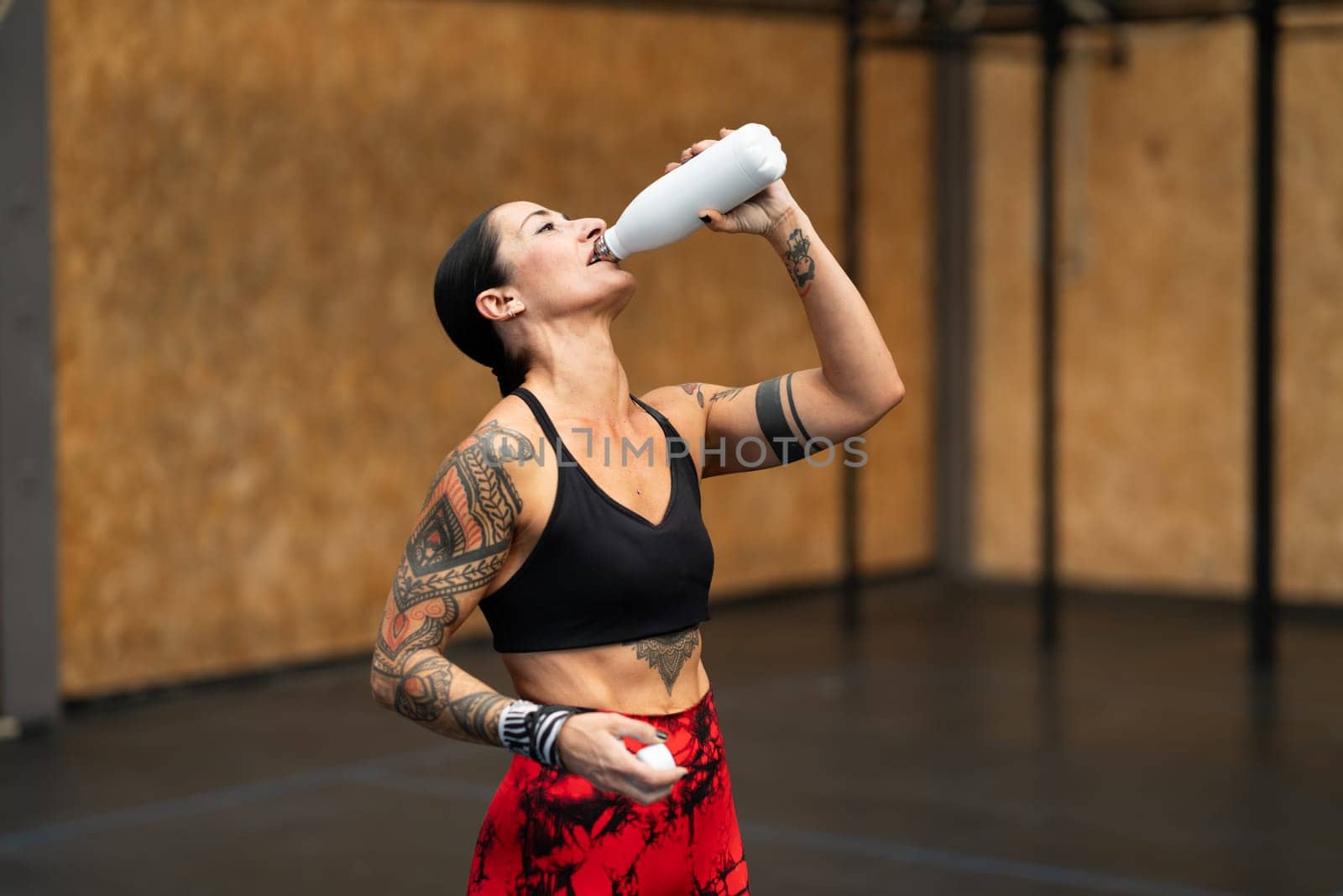 Horizontal photo with copy space of a tired athlete drinking water after working out in a gym