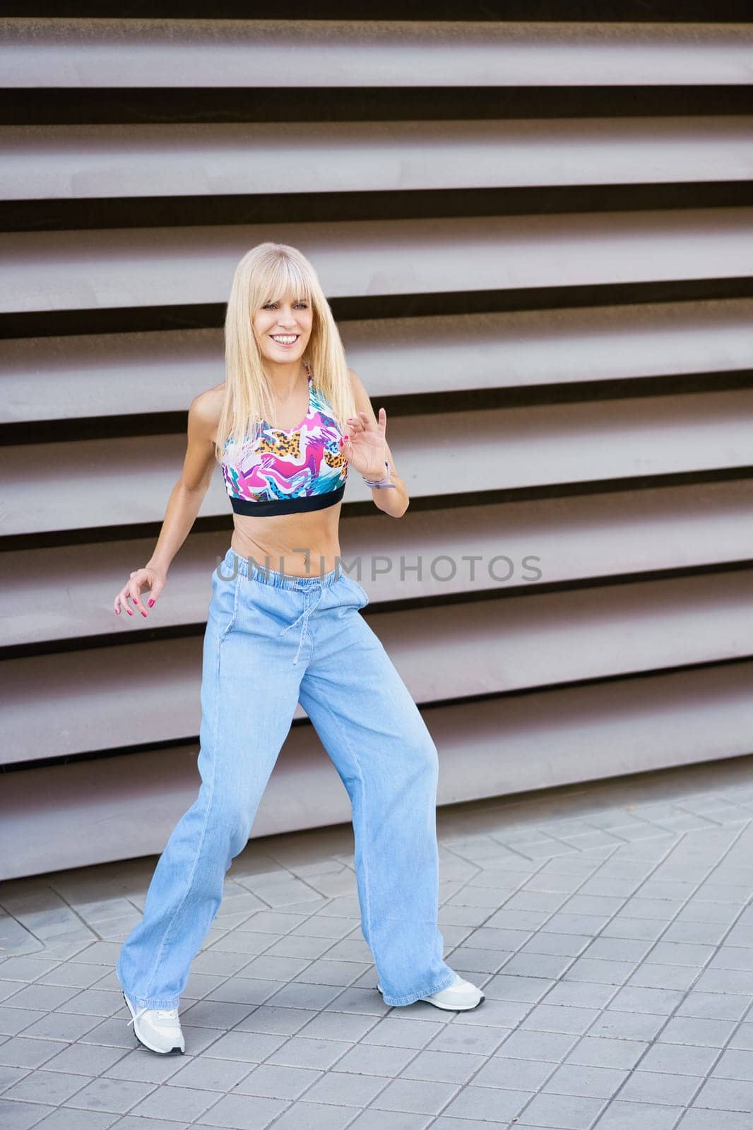 Vertical photo of a female blonde beauty and young modern dancer performing in an urban space