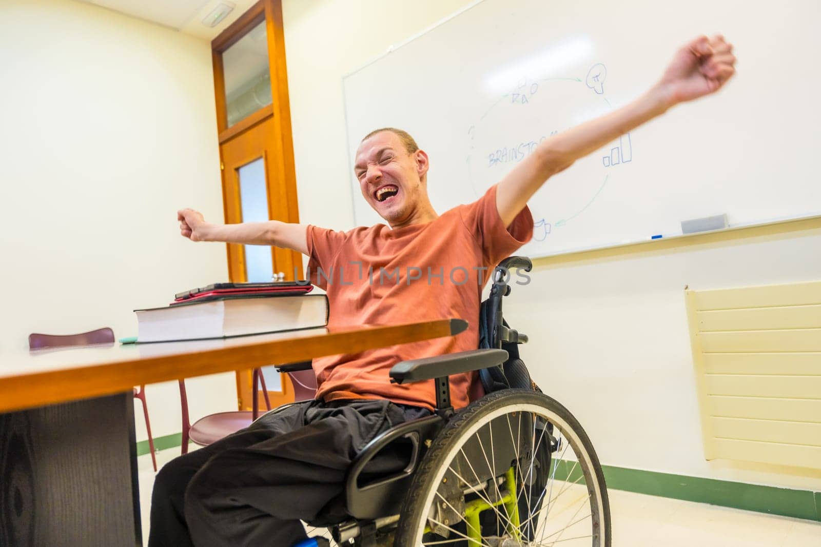 Low angle view photo of a caucasian happy man with disability celebrating raising arms in the university