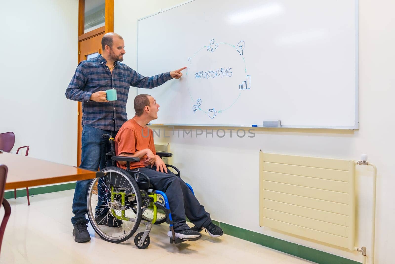Man with disability and colleague talking during a creative brainstorming in a meeting room