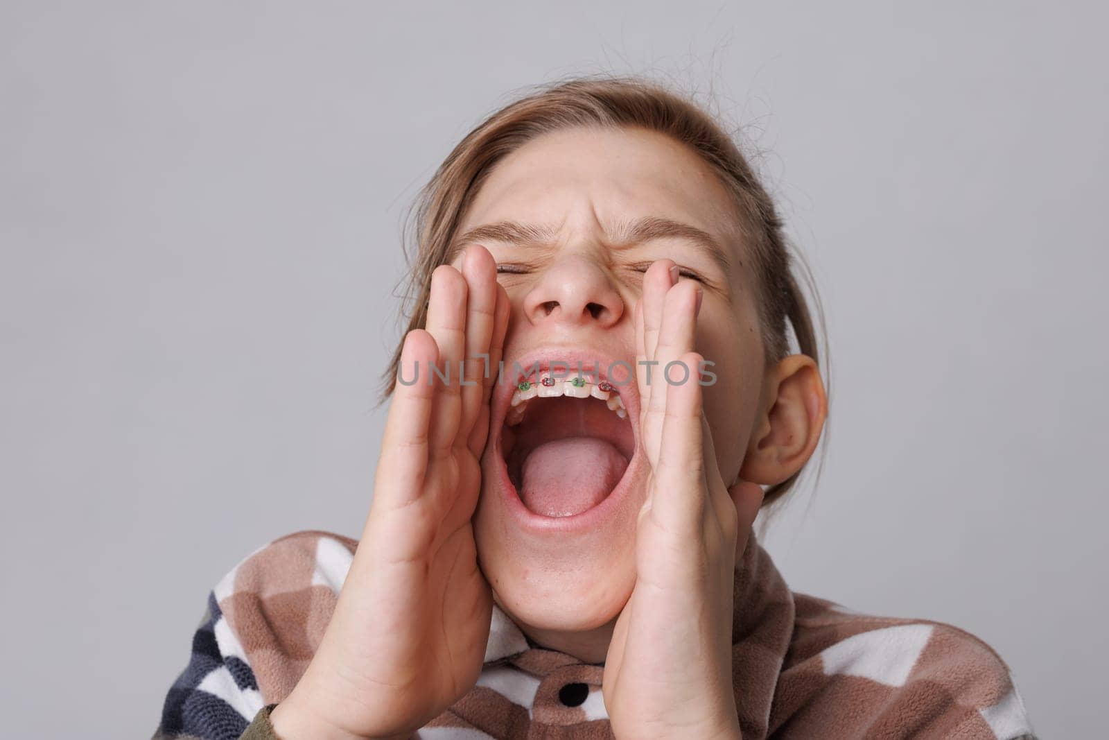 close-up portrait of a teenager with braces, the boy screams attracting attention, tell me urgently