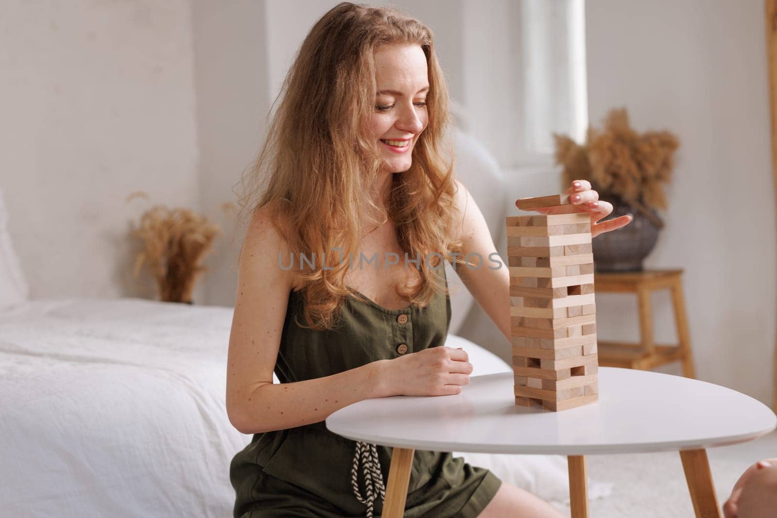 two women playing a board game made of wooden blocks at home, excitement and relaxation, mind development concept, hand motor skills,