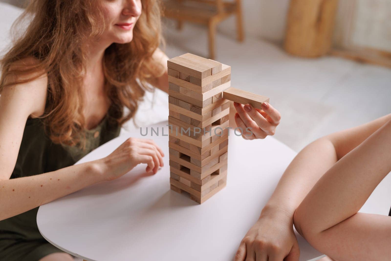 two women playing a board game made of wooden blocks at home, excitement and relaxation, mind development concept, hand motor skills,