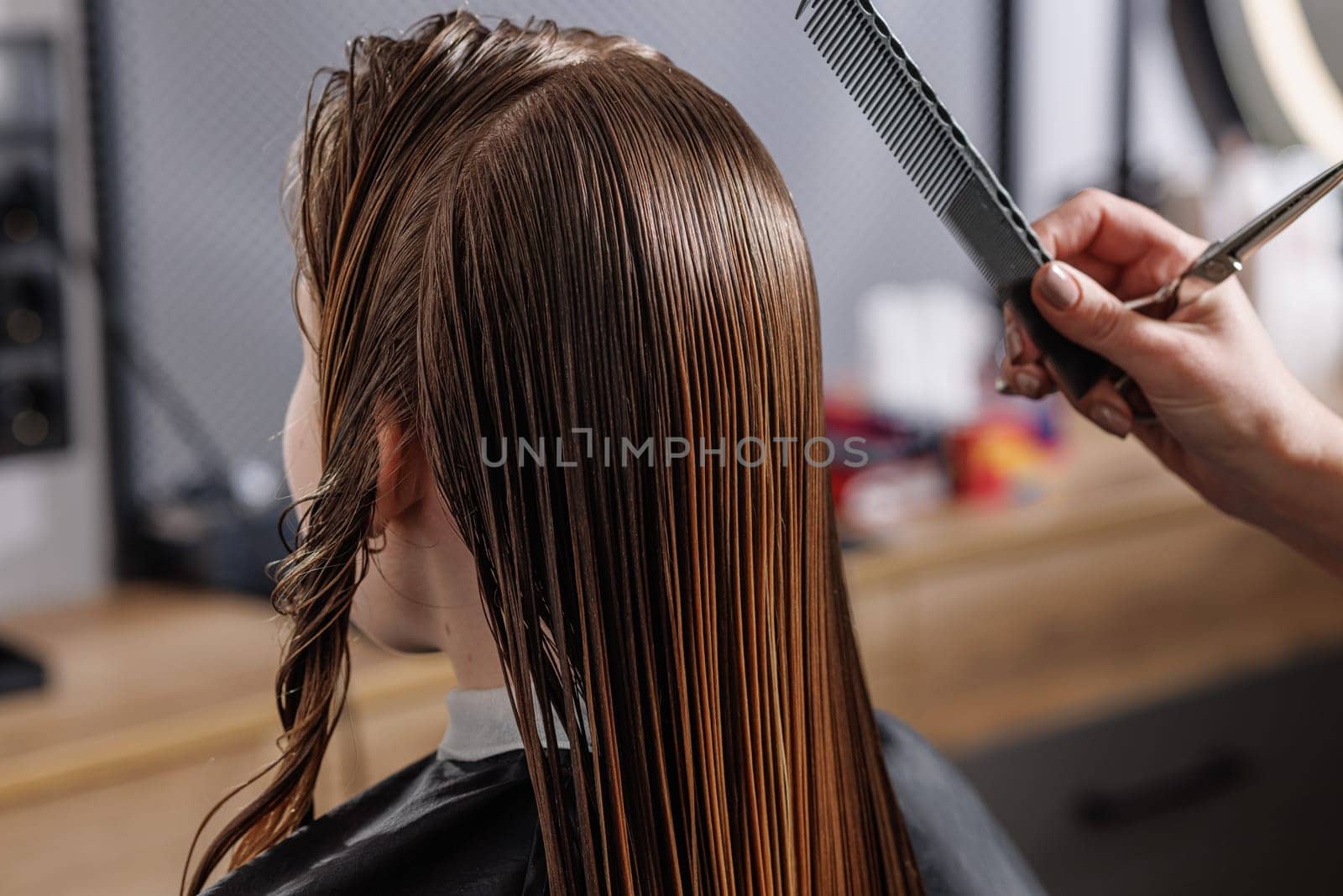 beauty master combing client's wet hair in beauty salon close-up, self-care concept, professional hair care