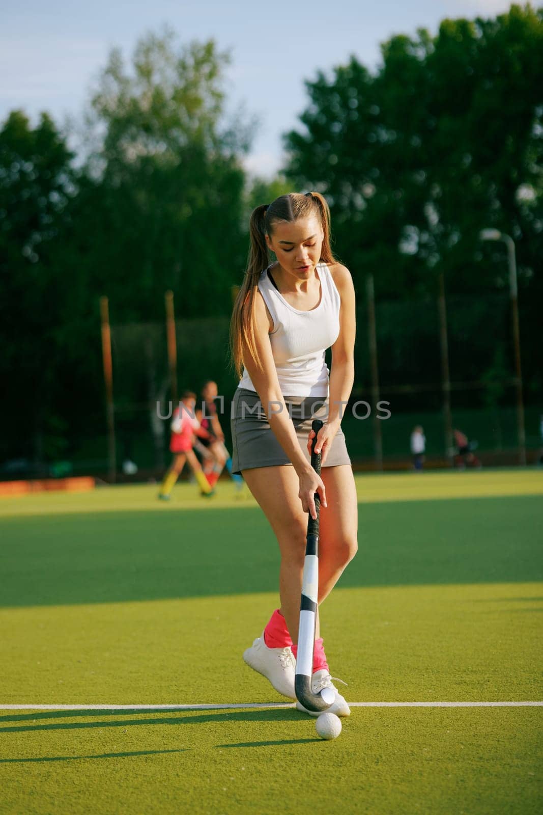 girl hockey player plays field hockey on a sunny day, female hockey player hits the ball with a stick, field hockey concept