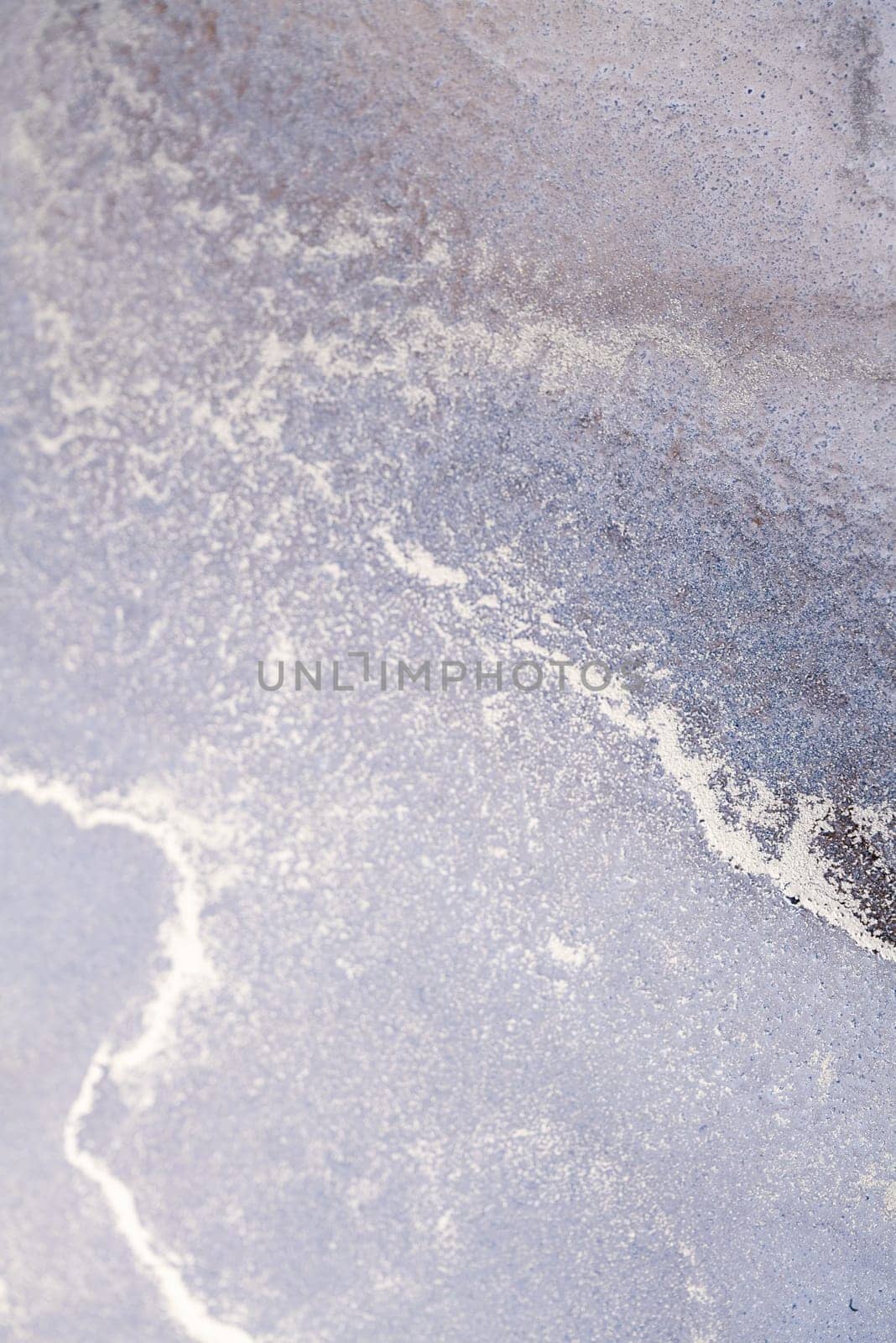A close-up view of a natural, textured surface featuring a silver-white line winding through a lavender background.