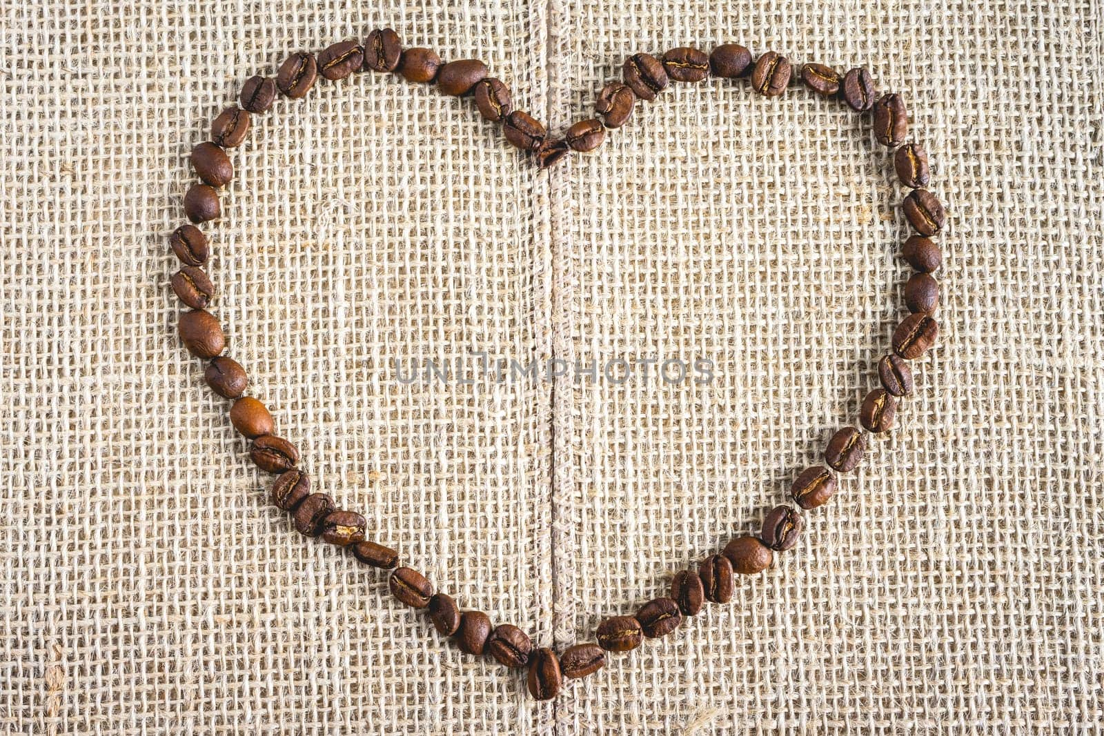 Coffee beans laying down in a heart shape, On a Burlap fabric. Background voor coffee related products.