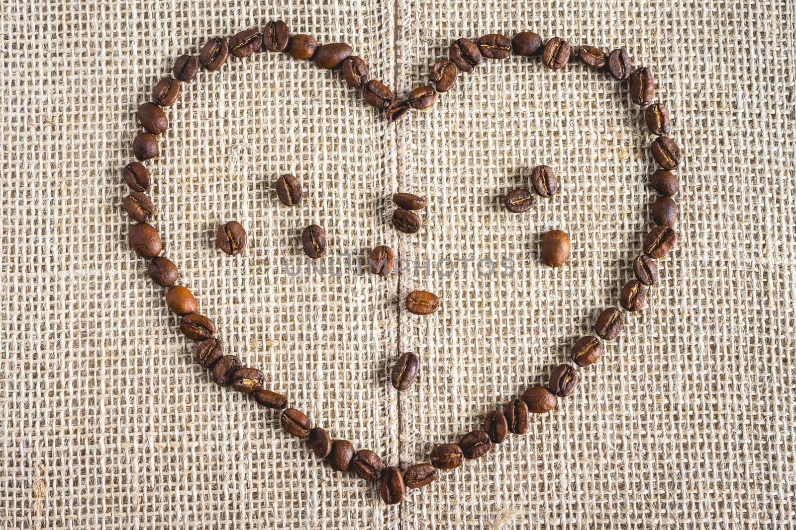 Coffee beans laying down in a heart shape, On a Burlap fabric. Background voor coffee related products.